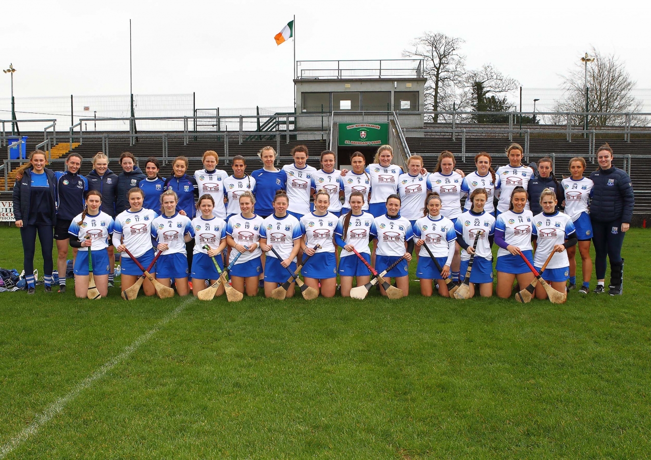 A women's team poses together on an outdoor field.