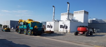 Construction vehicles parked outside an industrial building.