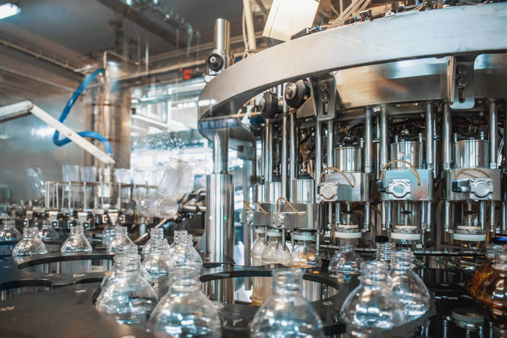 A close-up of a modern bottling line in a factory, with plastic bottles being filled by automated machinery.