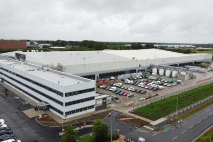 An aerial view of a large industrial facility with parking lots and surrounding roads.