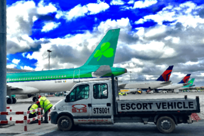 An escort vehicle parked next to an airplane on an airport tarmac.