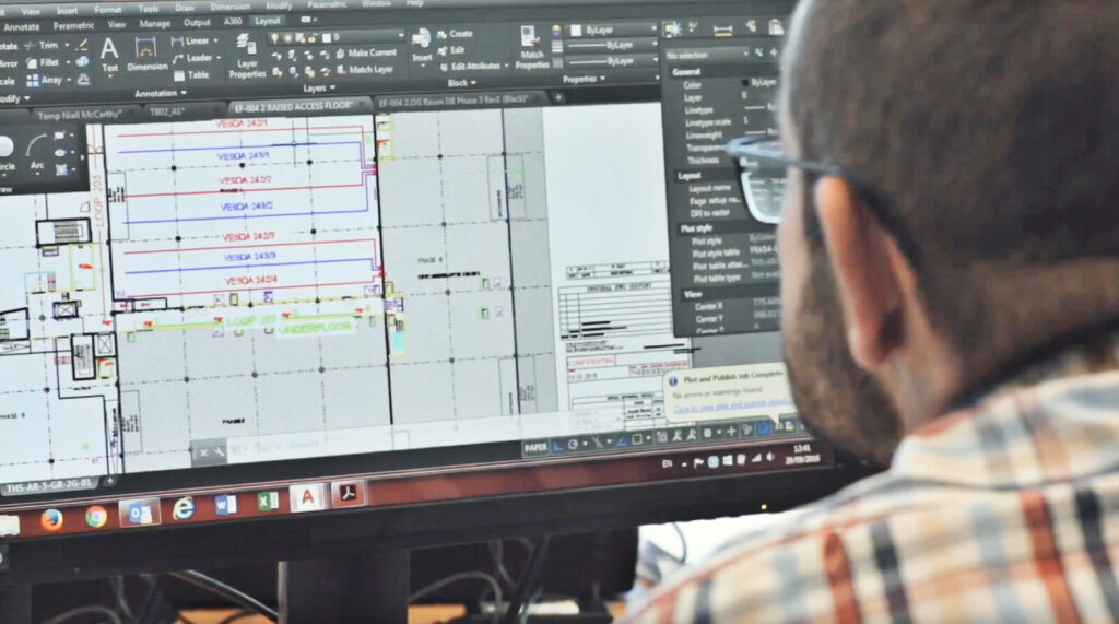 A person works on architectural plans displayed on a computer screen.