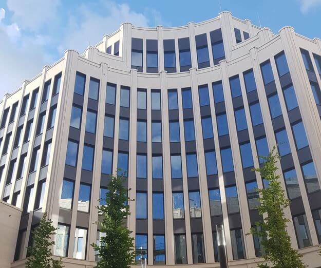 A modern office building with tall windows and a curved facade