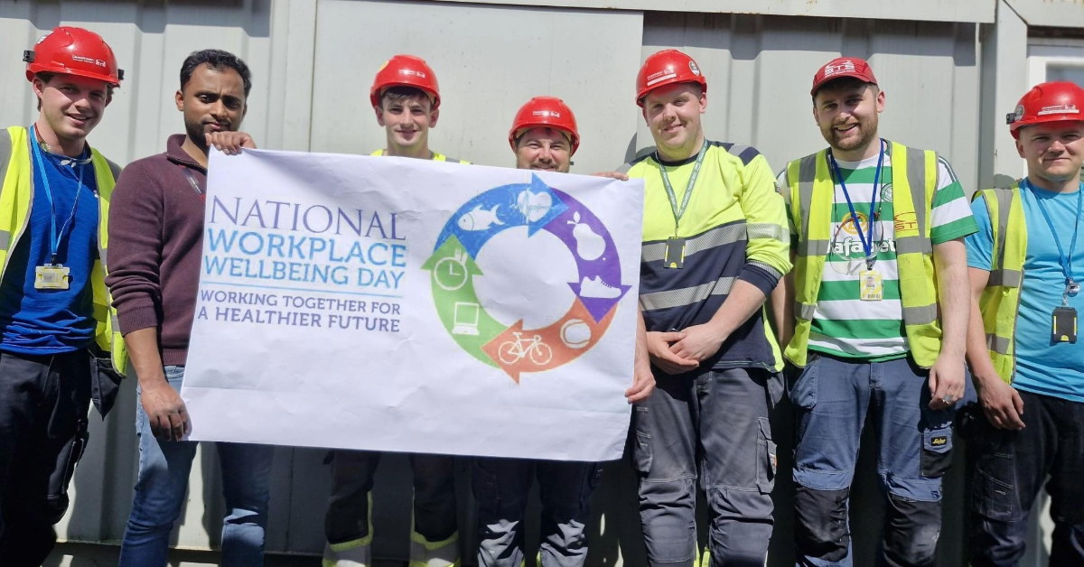 Workplace wellbeing Day. People from STS Group holding a banner to celebrate workplace wellbeing.
